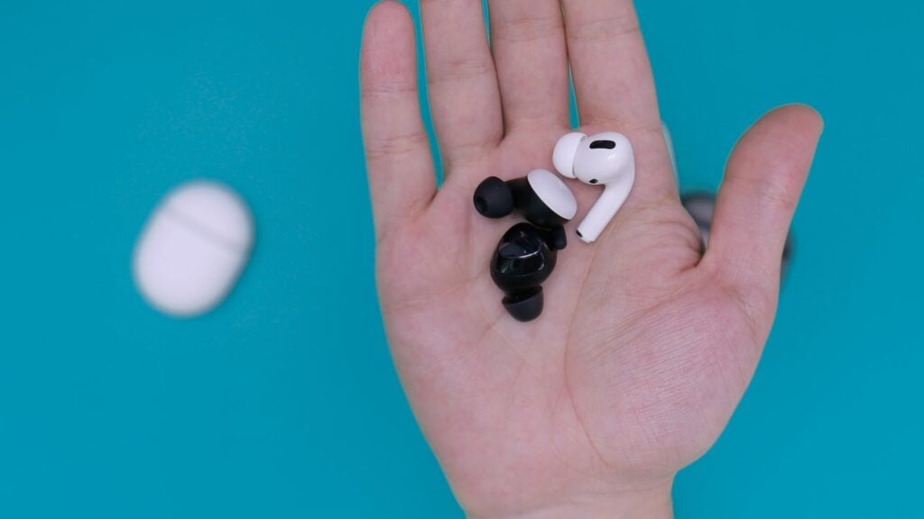 A hand holding a pair of airpods on a blue background. (No modifications made)