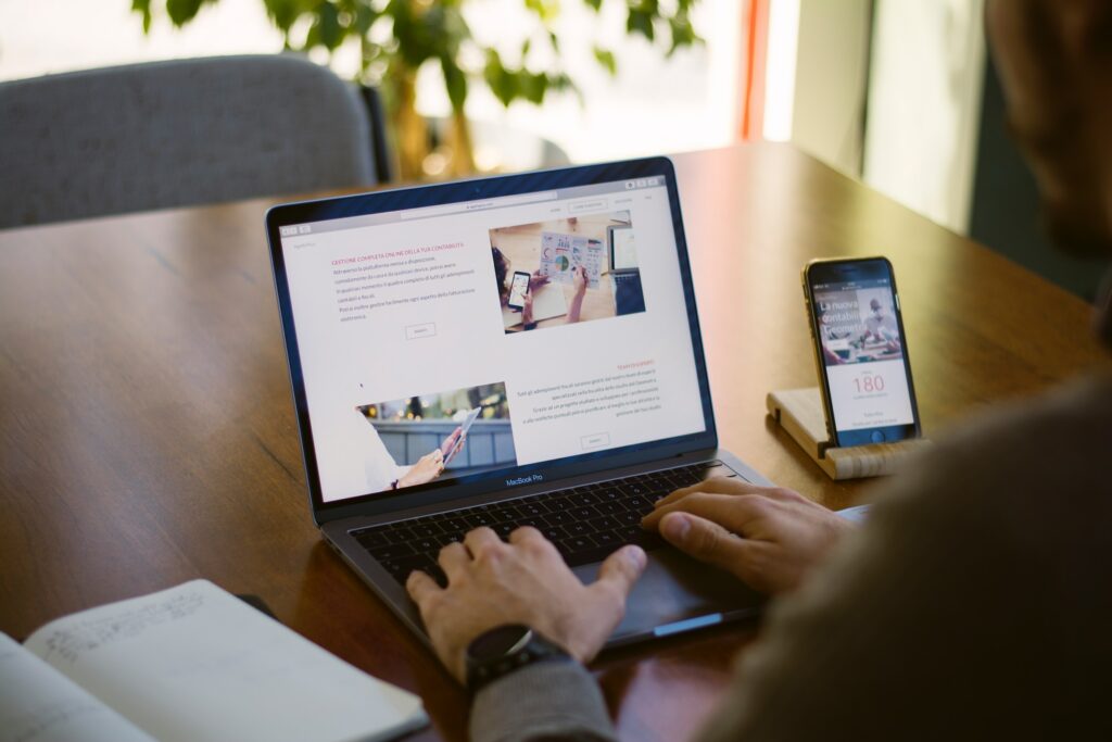 A man sitting at a desk with a laptop and cell phone, engaged in onsite optimization.