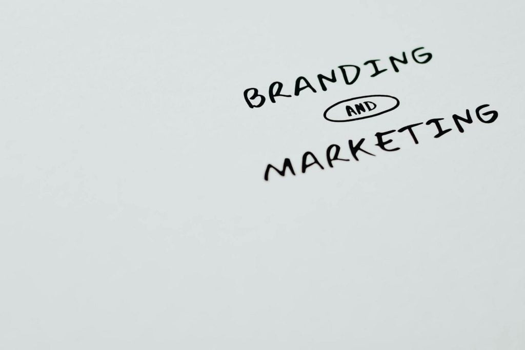 The words "BRANDING AND MARKETING" are handwritten on a plain surface, with "AND" inside an oval shape.
