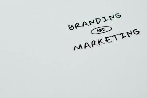 The words "BRANDING AND MARKETING" are handwritten on a plain surface, with "AND" inside an oval shape.