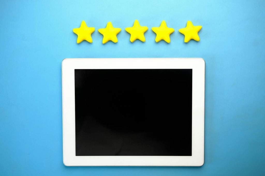 Tablet on a blue background with five yellow stars arranged above it.