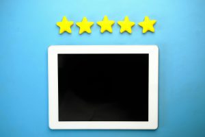 Tablet on a blue background with five yellow stars arranged above it.