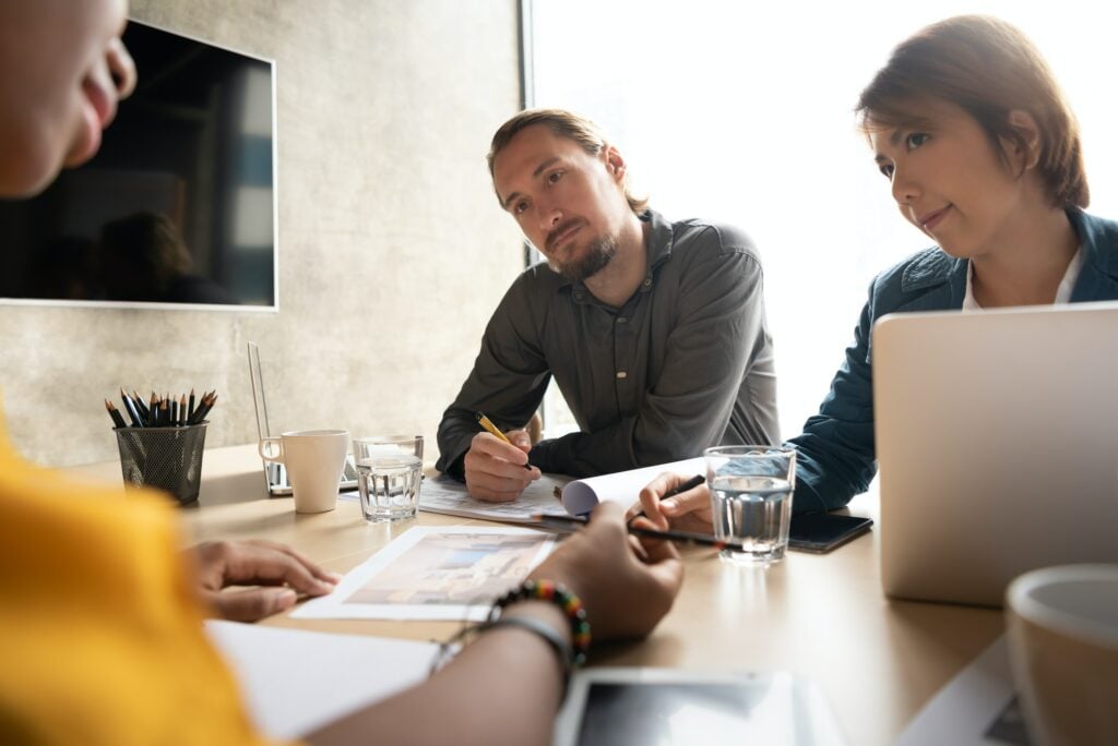 A group of stakeholders sitting around a table in a meeting.