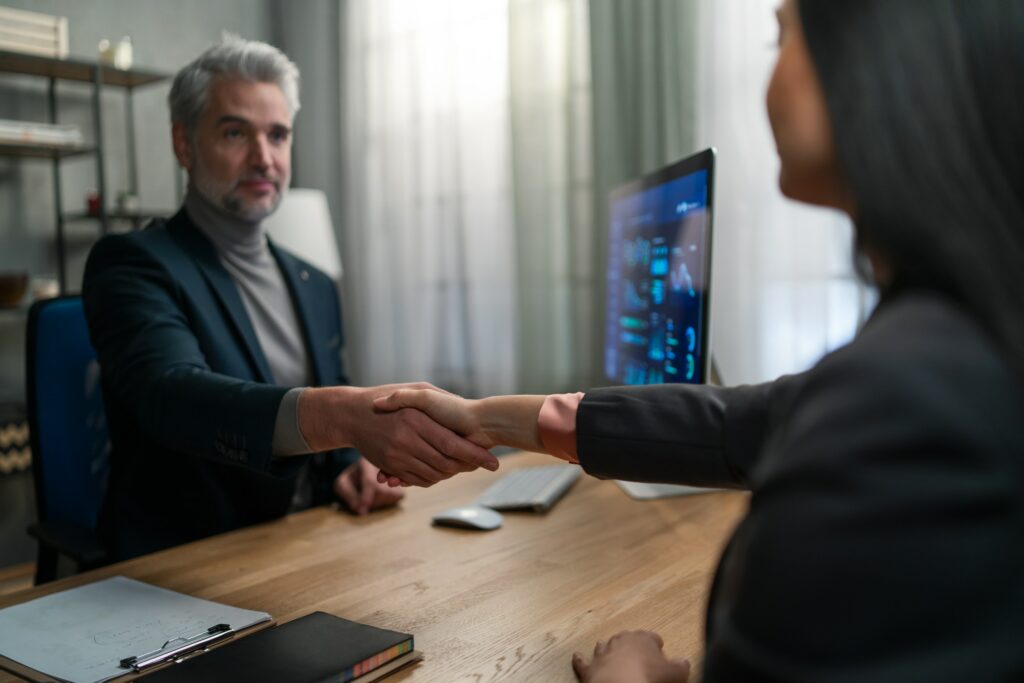 A businessman shaking hands with a woman at a desk while discussing "What is Black Rock".