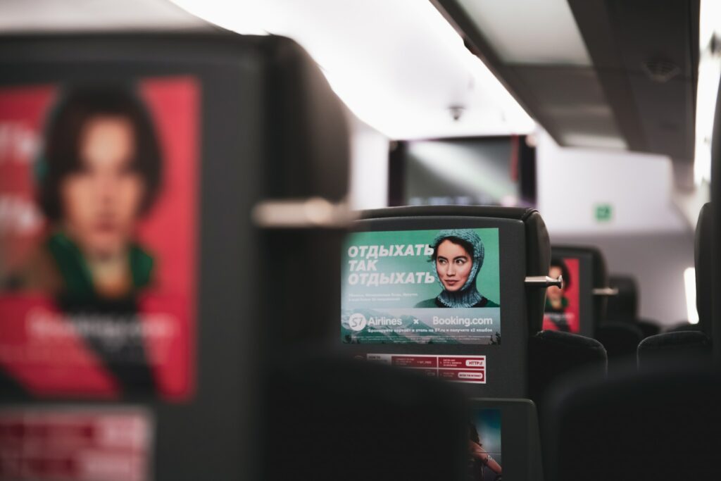 The Seats Of A Plane Feature Display Advertising Posters.