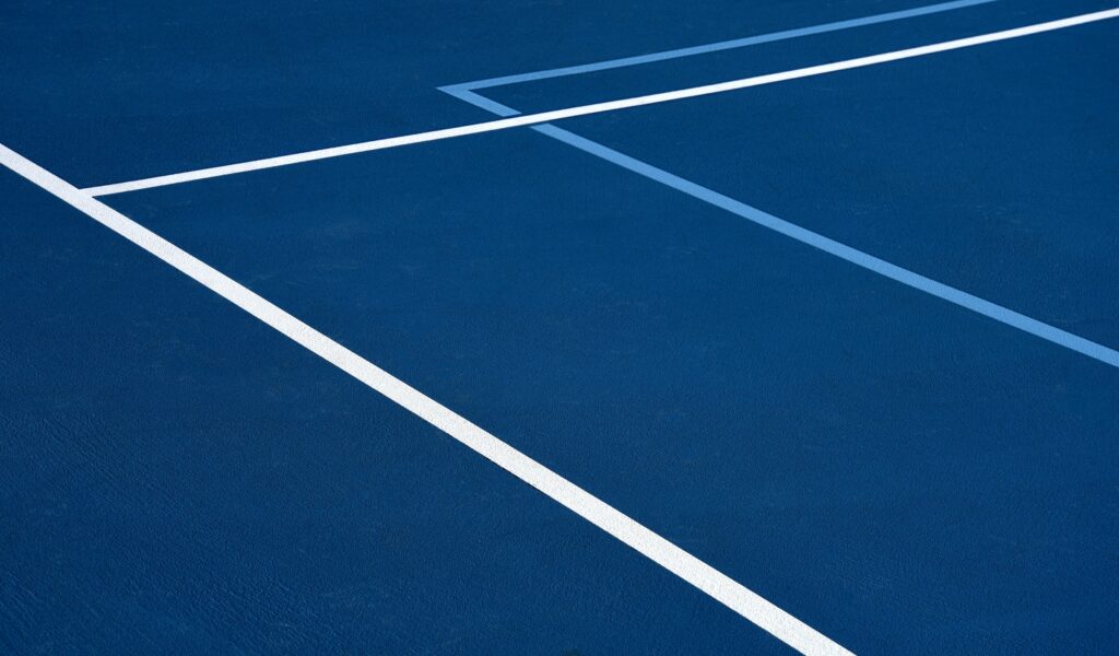 A Man Is Playing Pickleball On A Blue Court.
